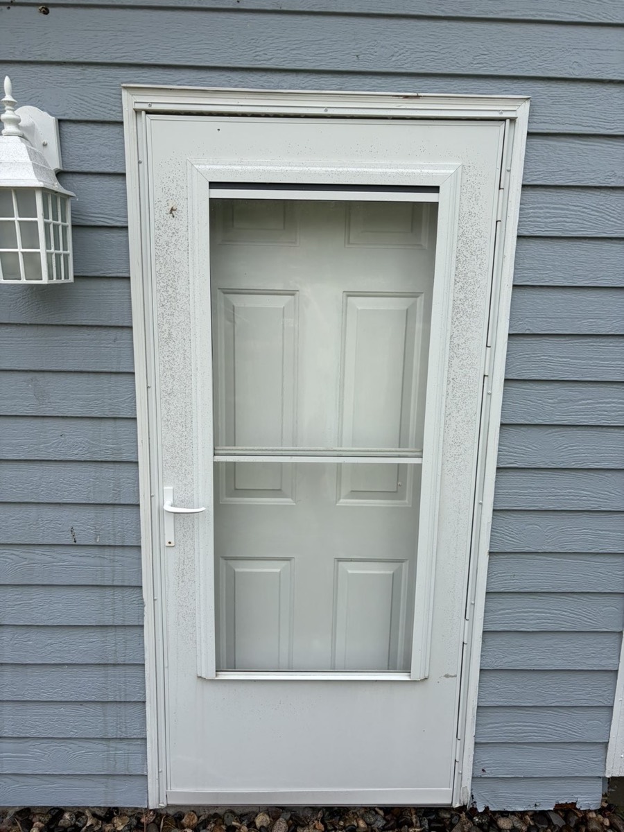 The same storm door before washing — dusty and weather-streaked