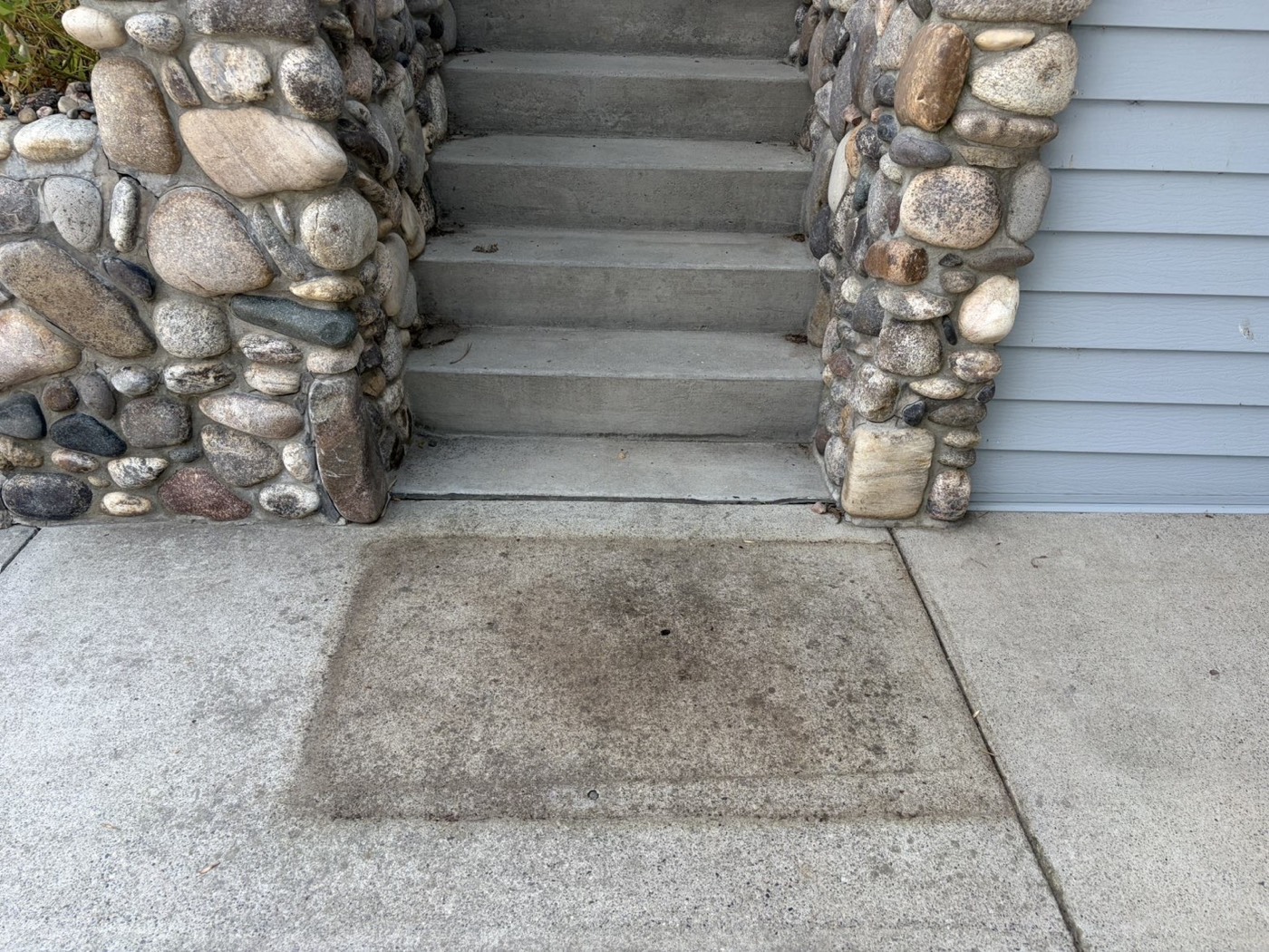 The same porch landing before cleaning — heavily stained concrete