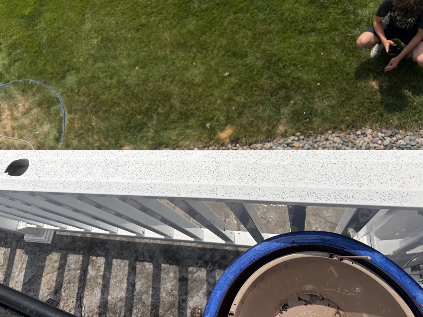 The same vinyl railing before washing — speckled with dirt and mildew
