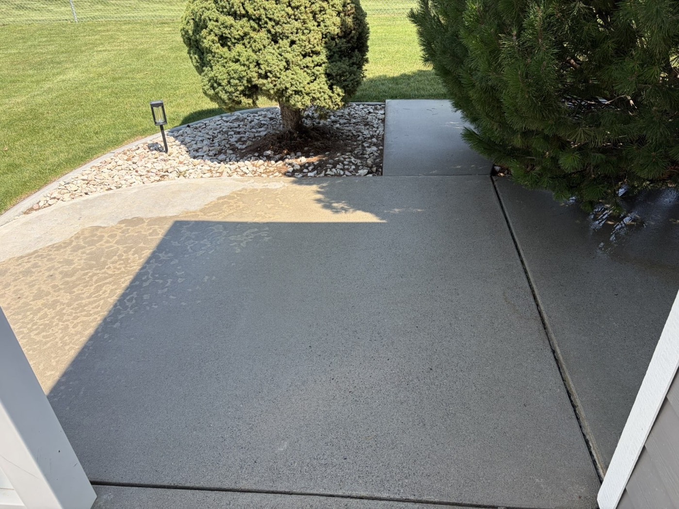 Clean concrete walkway beside a landscaped rock bed