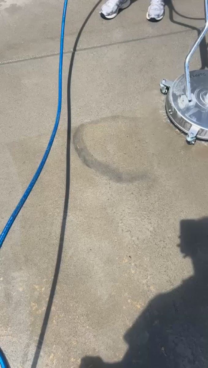 Surface cleaner and blue hose on a freshly cleaned concrete driveway